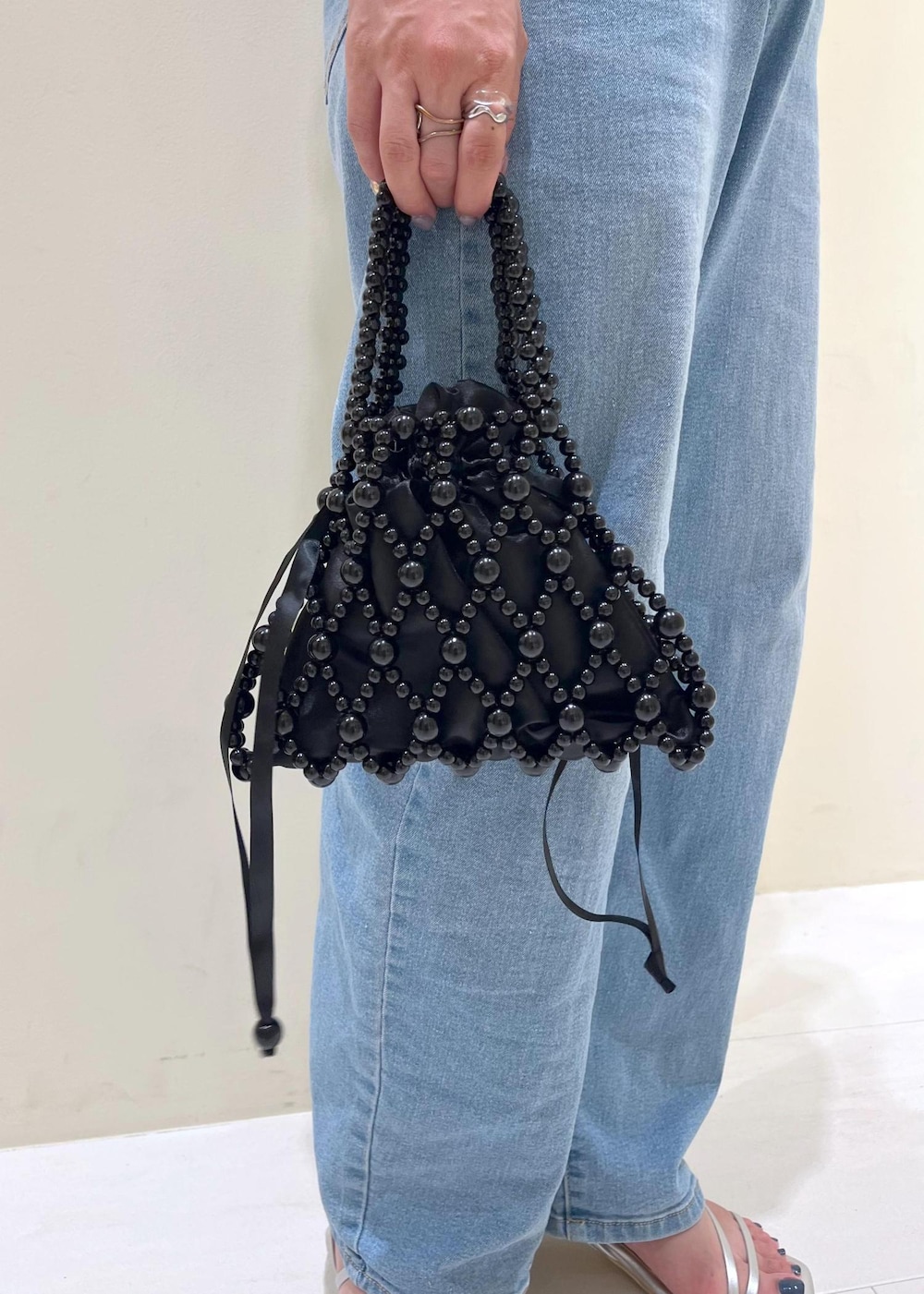 ブルー系のデニムパンツ、ブラック系のハンドバッグ、シルバー系のサンダルを着用したレディースの夏コーディネートの9枚目の写真