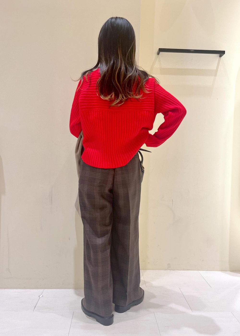 ブラック系のショルダーバッグ、レッド系のニット/セーター、ブラウン系のピーコートを着用したレディースの冬コーディネートの3枚目の写真