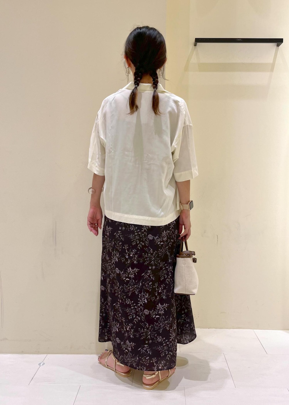 ブラウン系のトートバッグ、ゴールド系のサンダル、ブラック系のワンピースを着用したレディースの夏コーディネートの4枚目の写真