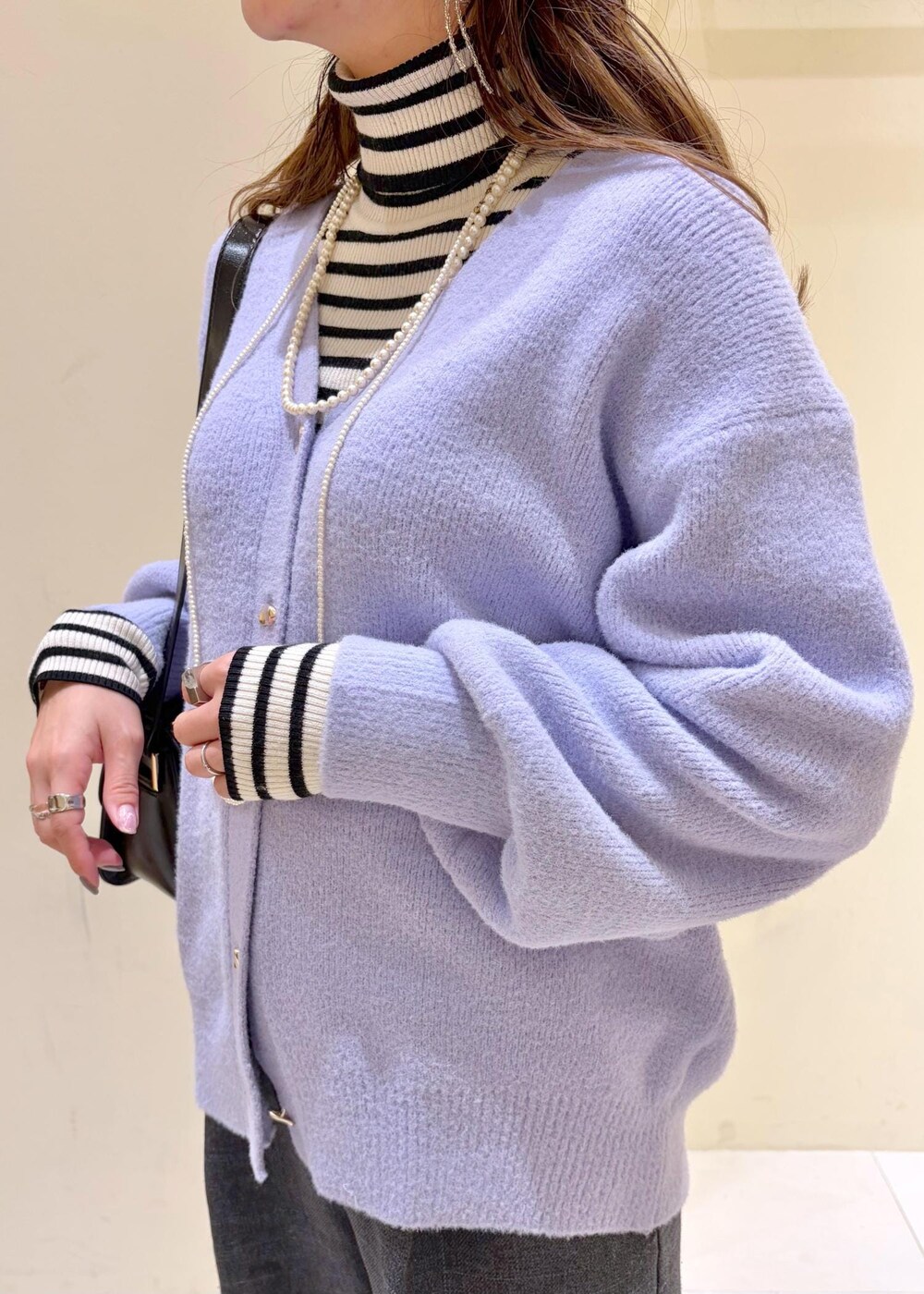 ブラック系のショルダーバッグ、ホワイト系のニット/セーター、グレー系のスラックスを着用したレディースの冬コーディネートの6枚目の写真