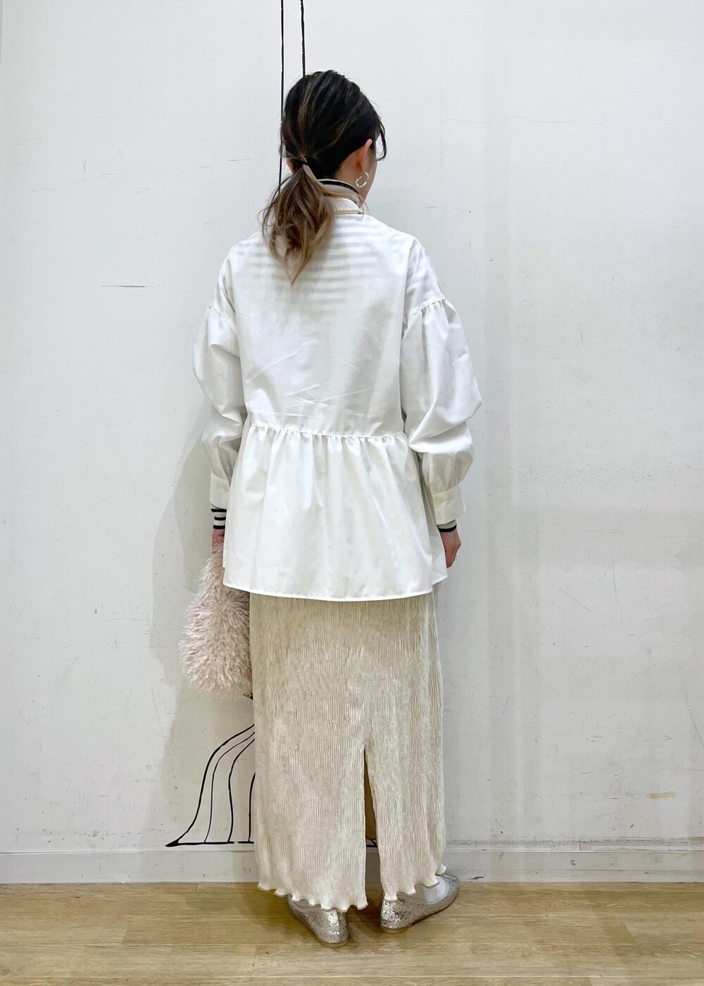 ベージュ系のハンドバッグ、ホワイト系のニット/セーター、シルバー系のバレエシューズを着用したレディースの冬コーディネートの5枚目の写真