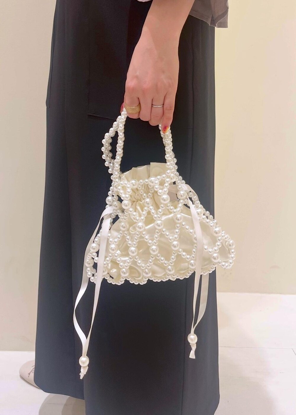 ホワイト系のバレエシューズ、ブラウン系のシャツ/ブラウス、ブラック系のジャンパースカートを着用したレディースの春コーディネートの9枚目の写真