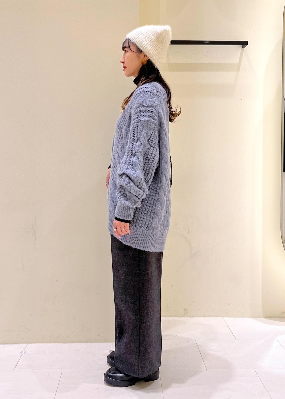 ブラック系のショルダーバッグ、ブラック系のニット/セーター、グレー系のスラックスを着用したレディースの秋コーディネートの4枚目の写真