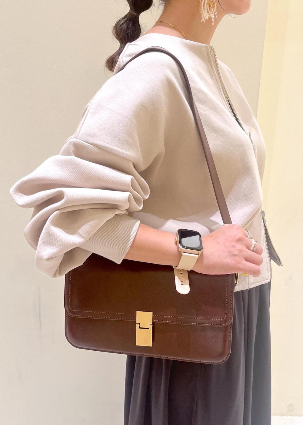 レッド系のショルダーバッグ、ベージュ系のパンプス、ベージュ系のカーディガン/ボレロを着用したレディースの秋コーディネートの9枚目の写真