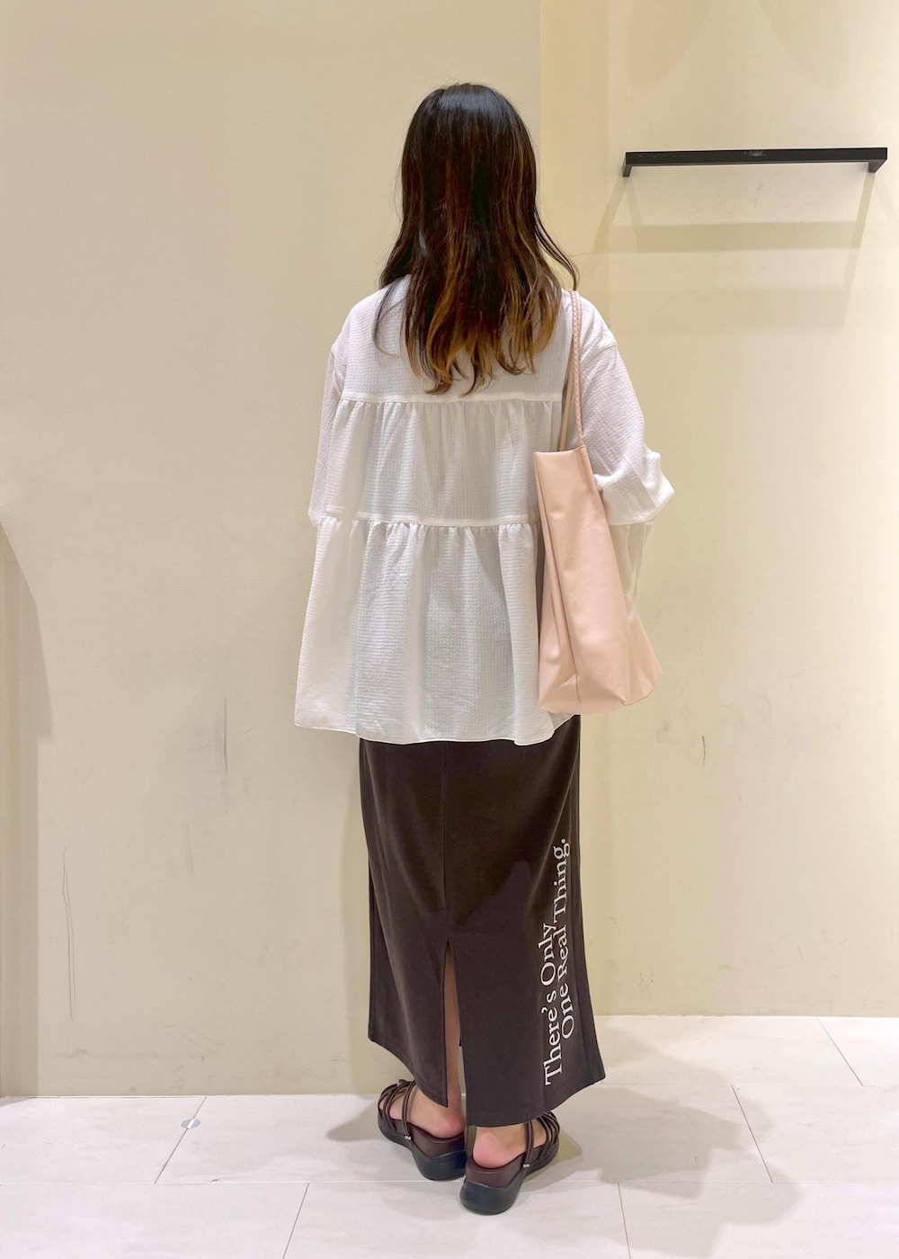 ピンク系のトートバッグ、ブラウン系のサンダル、ホワイト系のシャツ/ブラウスを着用したレディースの夏コーディネートの3枚目の写真