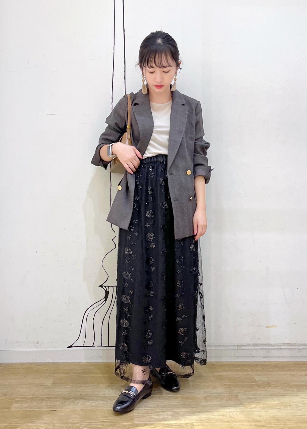 ブラック系のスカート、ベージュ系のTシャツ/カットソー、ブラウン系のテーラードジャケットを着用したレディースの秋コーディネートの2枚目の写真