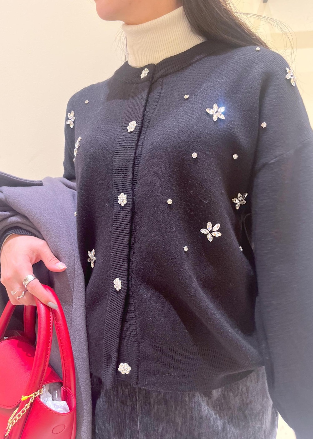 グレー系のスカート、ブラック系のカーディガン/ボレロ、ホワイト系のニット/セーターを着用したレディースの冬コーディネートの5枚目の写真