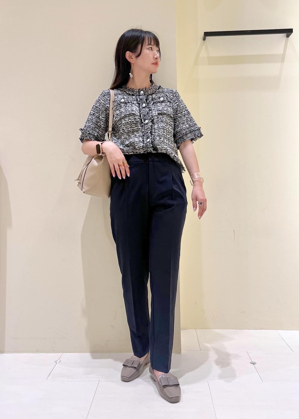 ブルー系のスラックス、ベージュ系のショルダーバッグ、ブラック系のカーディガン/ボレロを着用したレディースの夏コーディネートの2枚目の写真
