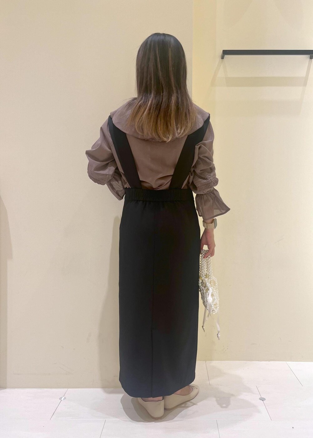 ホワイト系のバレエシューズ、ブラウン系のシャツ/ブラウス、ブラック系のジャンパースカートを着用したレディースの春コーディネートの6枚目の写真