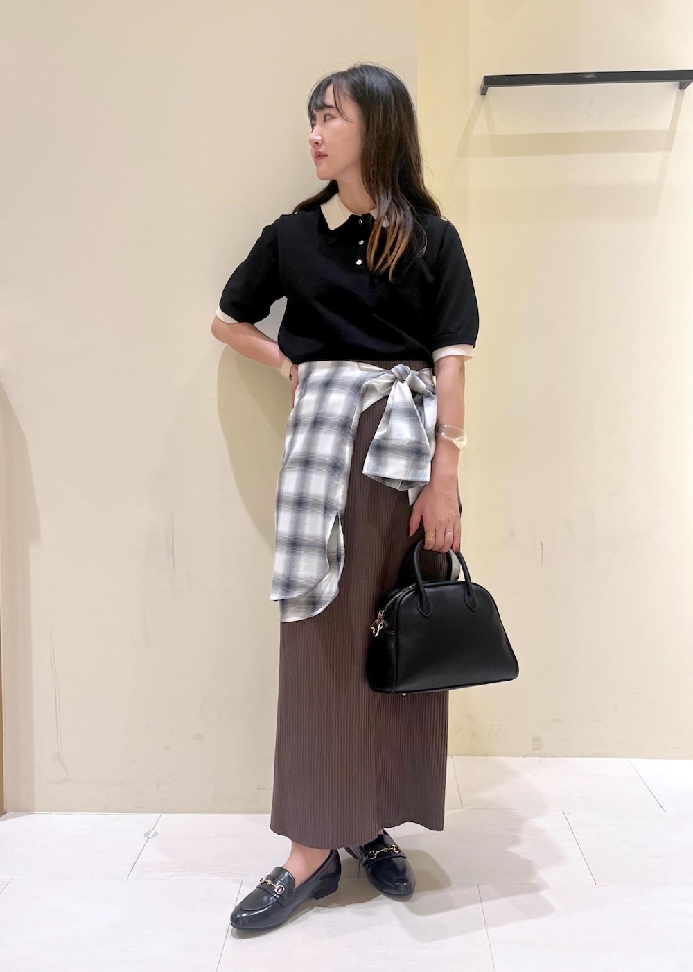 ブラック系のスカート、ブラック系のボストンバッグ、ブラック系のポロシャツを着用したレディースの夏コーディネートの2枚目の写真