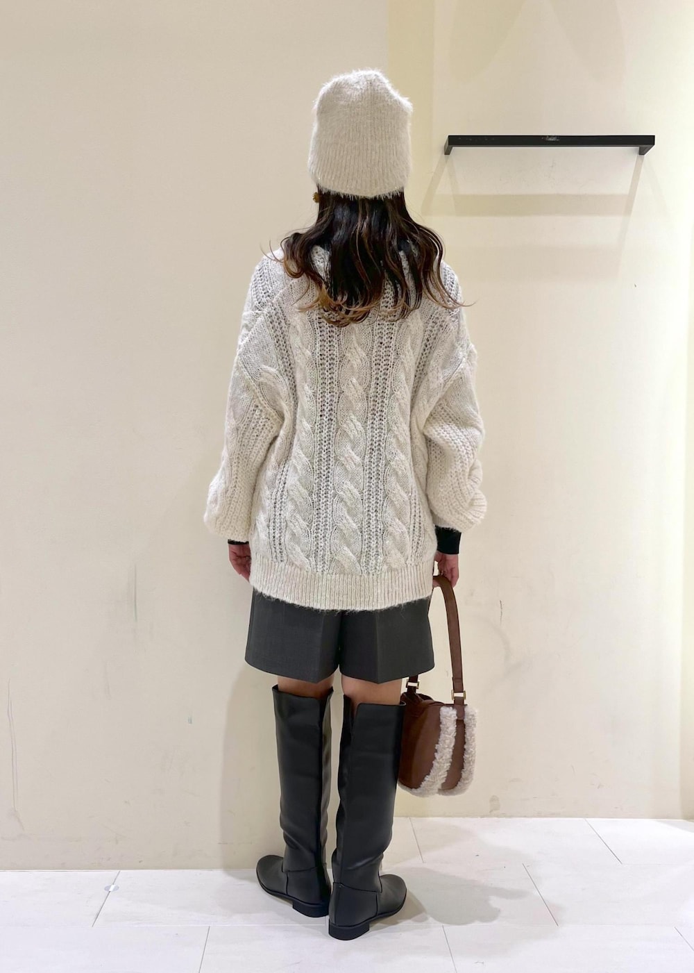 ブラック系のニット/セーター、ブラック系のブーツ、ブラウン系のショルダーバッグを着用したレディースの秋コーディネートの3枚目の写真