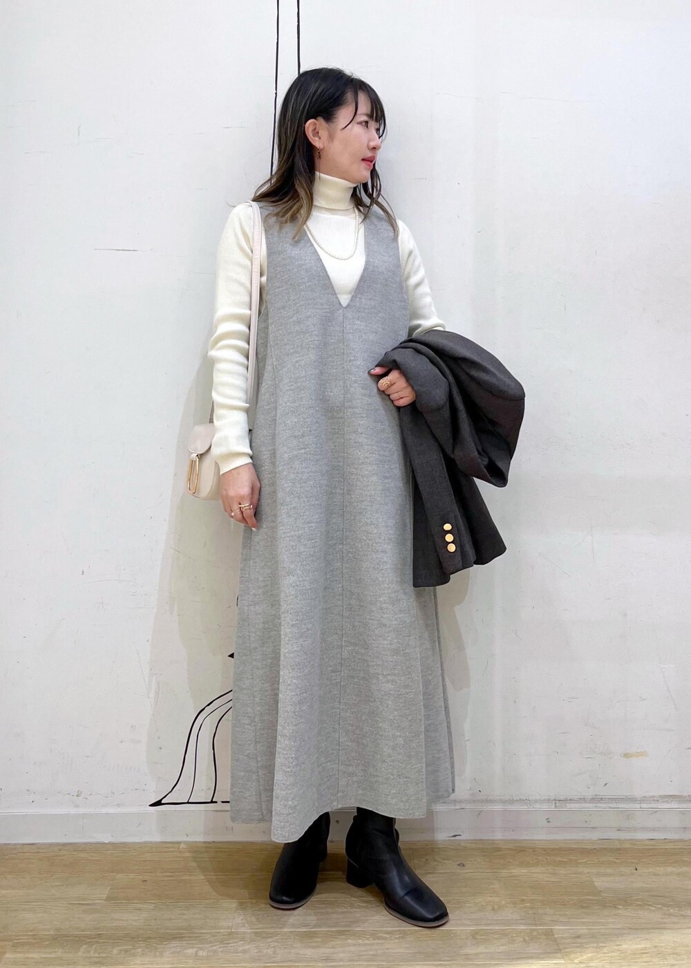 ホワイト系のショルダーバッグ、ブラック系のブーツ、ホワイト系のニット/セーターを着用したレディースの冬コーディネートの7枚目の写真