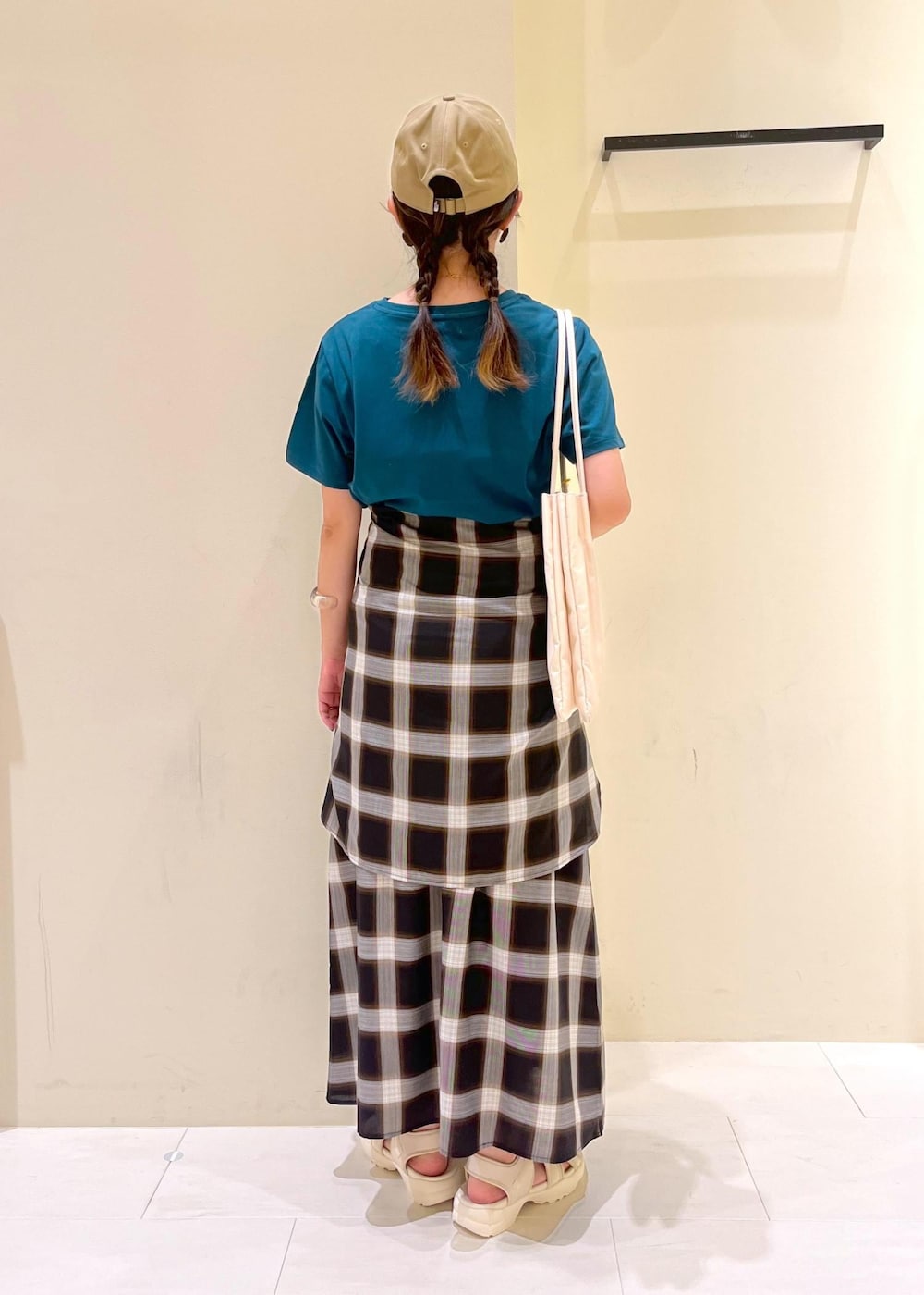 ホワイト系のトートバッグ、ホワイト系のサンダル、ブラック系のワンピースを着用したレディースの夏コーディネートの3枚目の写真