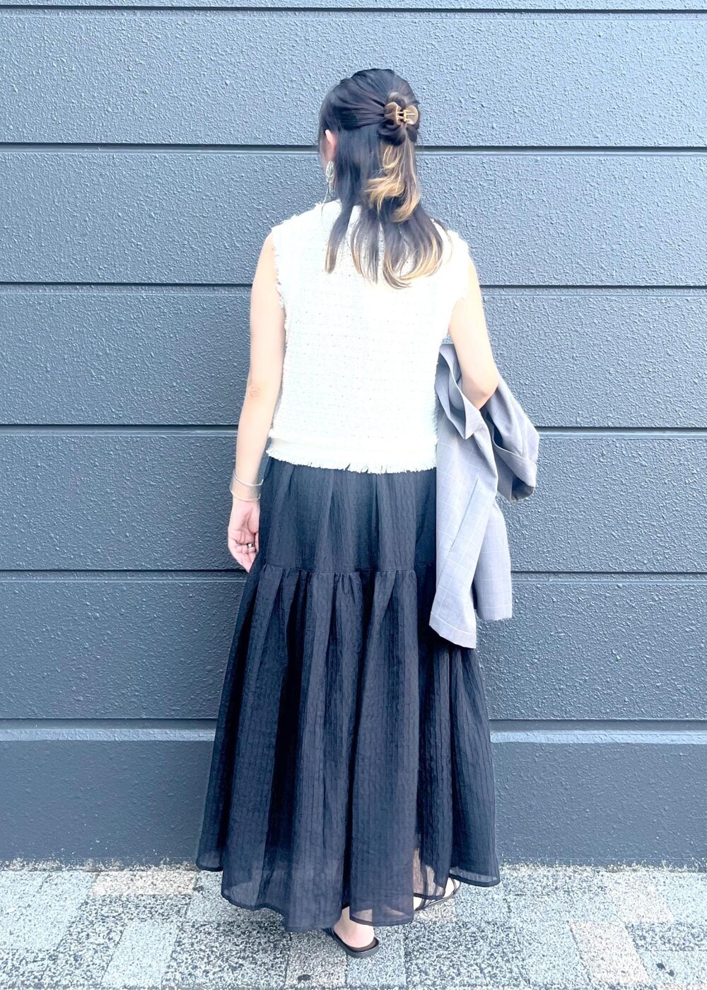 グレー系のテーラードジャケット、ブラウン系のトートバッグ、ブラック系のスカートを着用したレディースの夏コーディネートの4枚目の写真