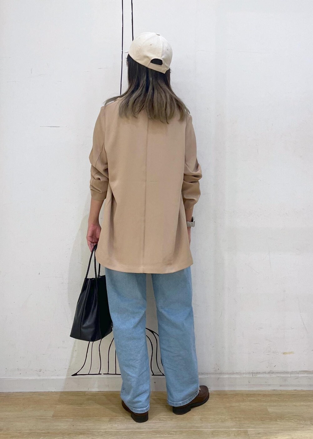 ブラウン系のローファー、ブラック系のトートバッグ、ブルー系のデニムパンツを着用したレディースの秋コーディネートの5枚目の写真