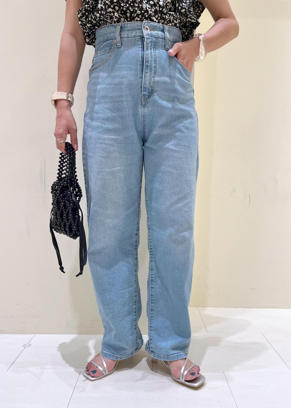 ブルー系のデニムパンツ、ブラック系のハンドバッグ、シルバー系のサンダルを着用したレディースの夏コーディネートの7枚目の写真