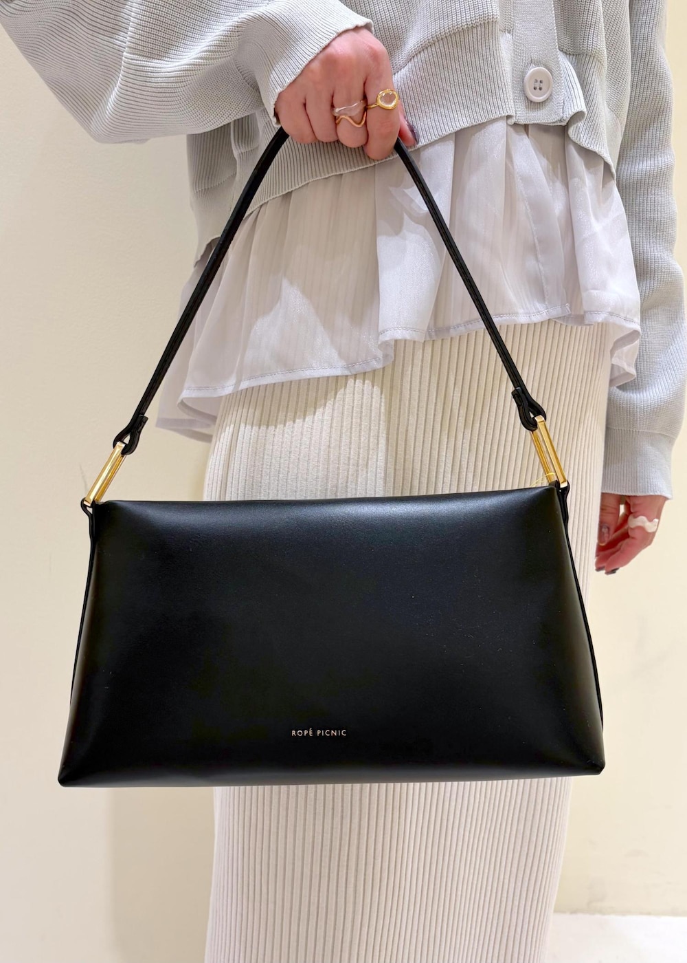 ブラック系のショルダーバッグ、ブラック系のパンプス、ホワイト系のスカートを着用したレディースの春コーディネートの9枚目の写真