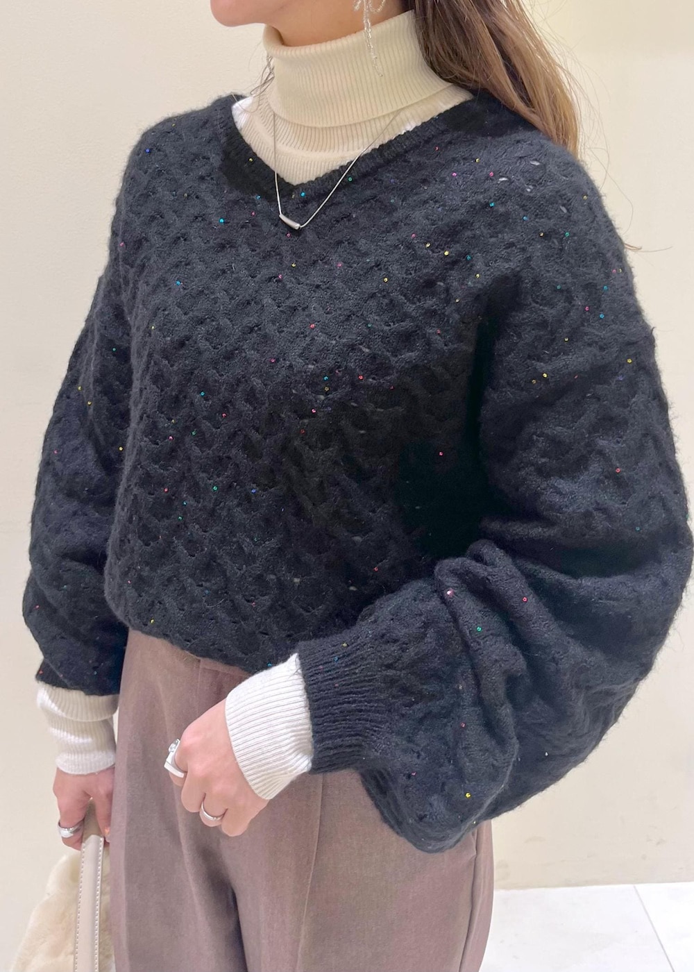 ベージュ系のスラックス、ホワイト系のニット/セーター、ベージュ系のショルダーバッグを着用したレディースの冬コーディネートの5枚目の写真