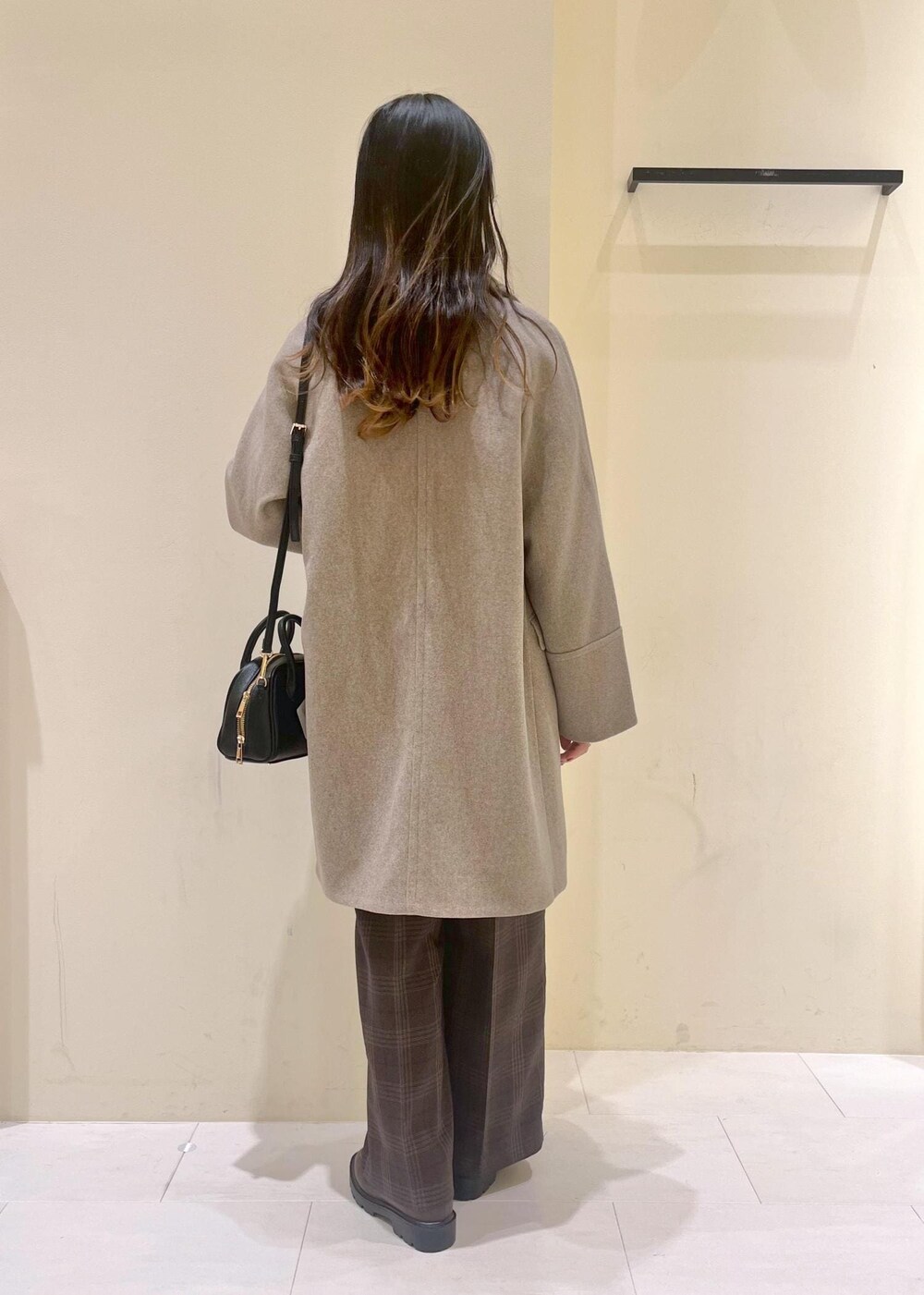 ブラック系のショルダーバッグ、レッド系のニット/セーター、ブラウン系のピーコートを着用したレディースの秋コーディネートの3枚目の写真