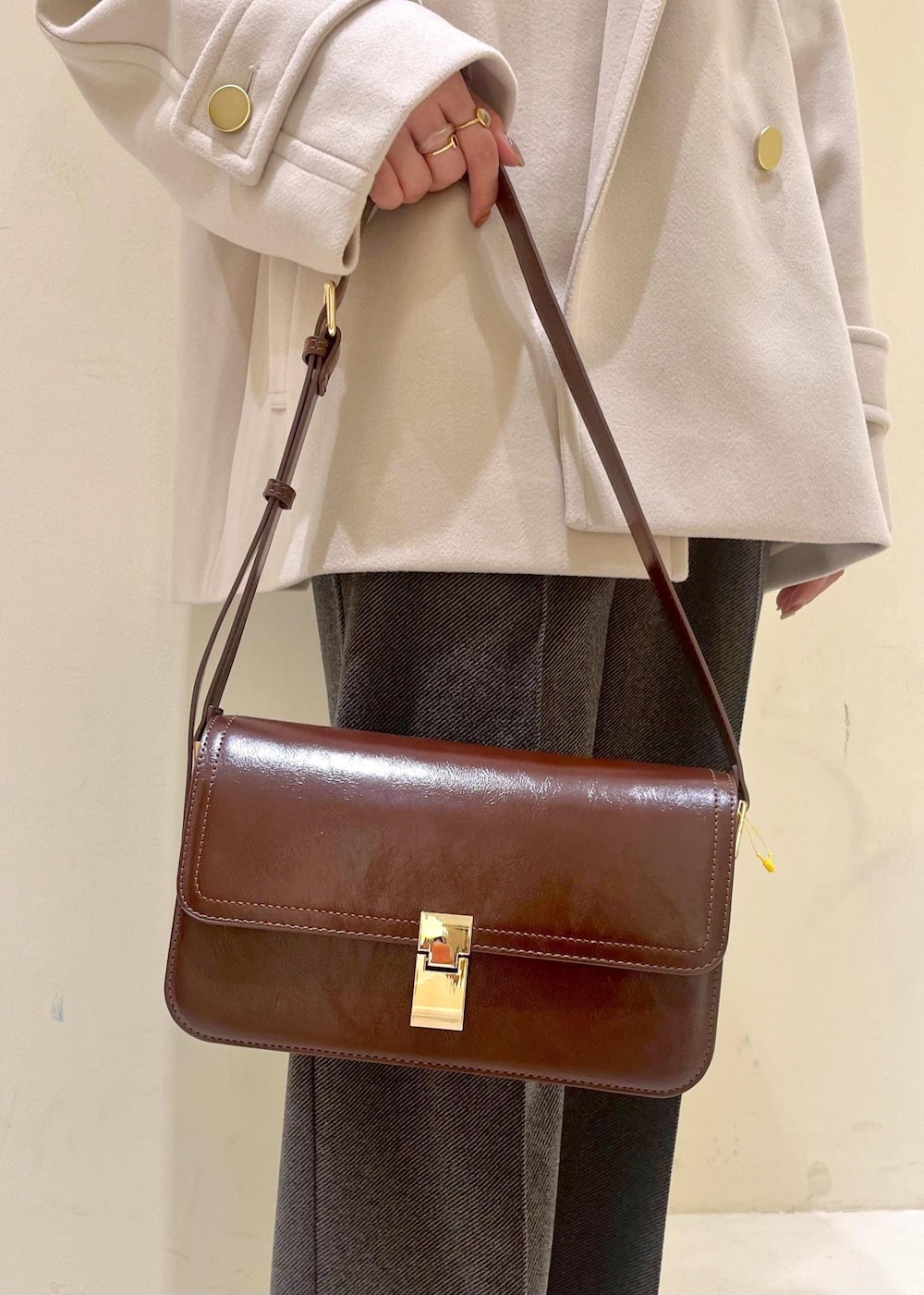 レッド系のショルダーバッグ、ホワイト系のニット/セーター、ベージュ系のその他アウターを着用したレディースの冬コーディネートの7枚目の写真