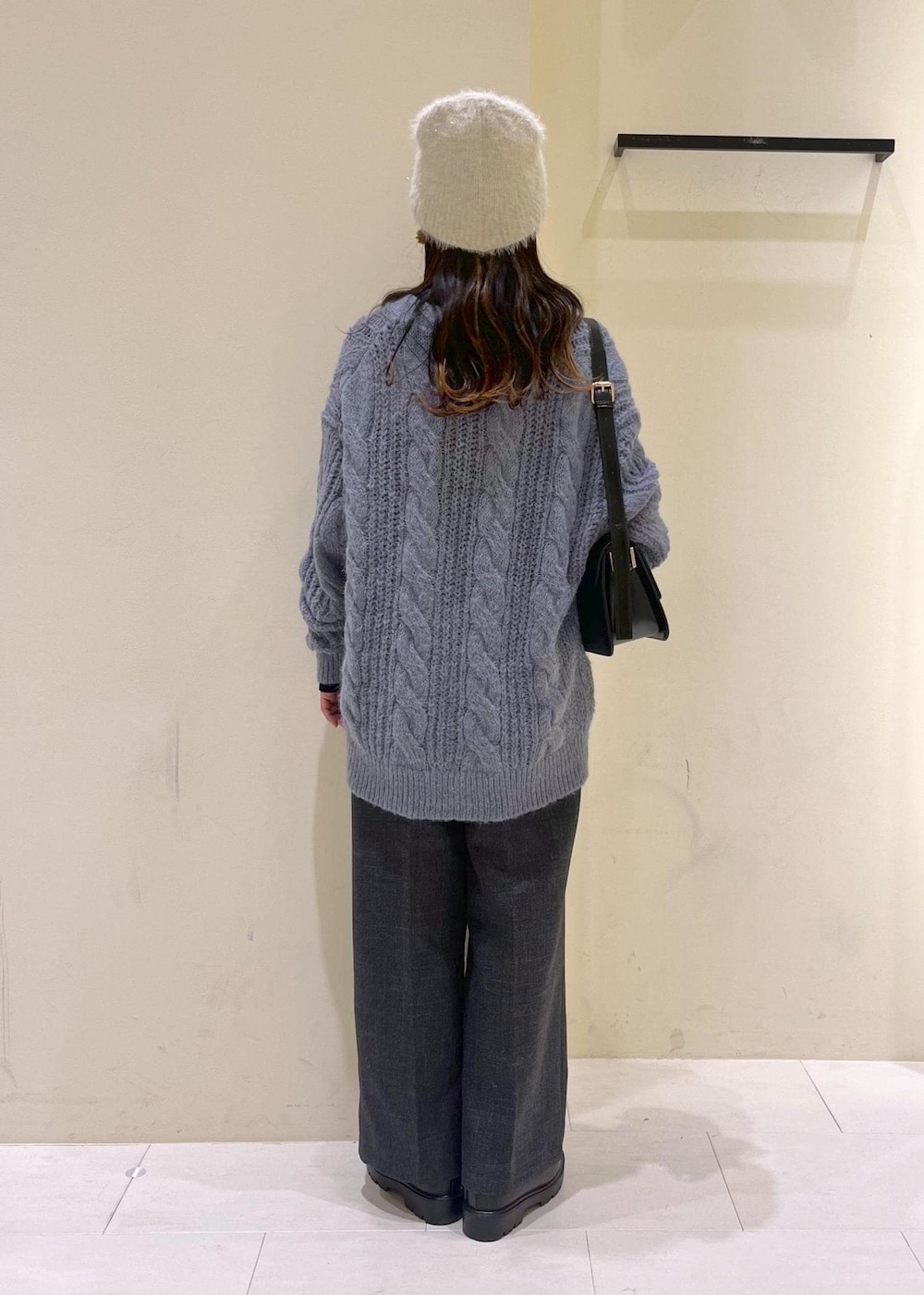 ブラック系のショルダーバッグ、ブラック系のニット/セーター、グレー系のスラックスを着用したレディースの秋コーディネートの3枚目の写真