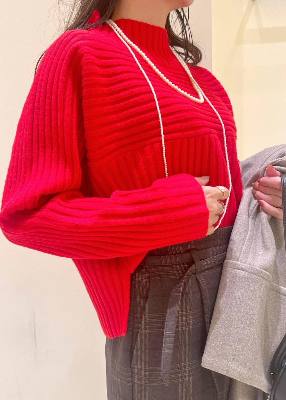 ブラック系のショルダーバッグ、レッド系のニット/セーター、ブラウン系のピーコートを着用したレディースの冬コーディネートの4枚目の写真