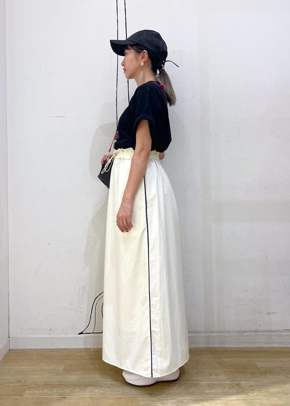 ホワイト系のスニーカー、グレー系のショルダーバッグ、ホワイト系のスカートを着用したレディースの夏コーディネートの3枚目の写真