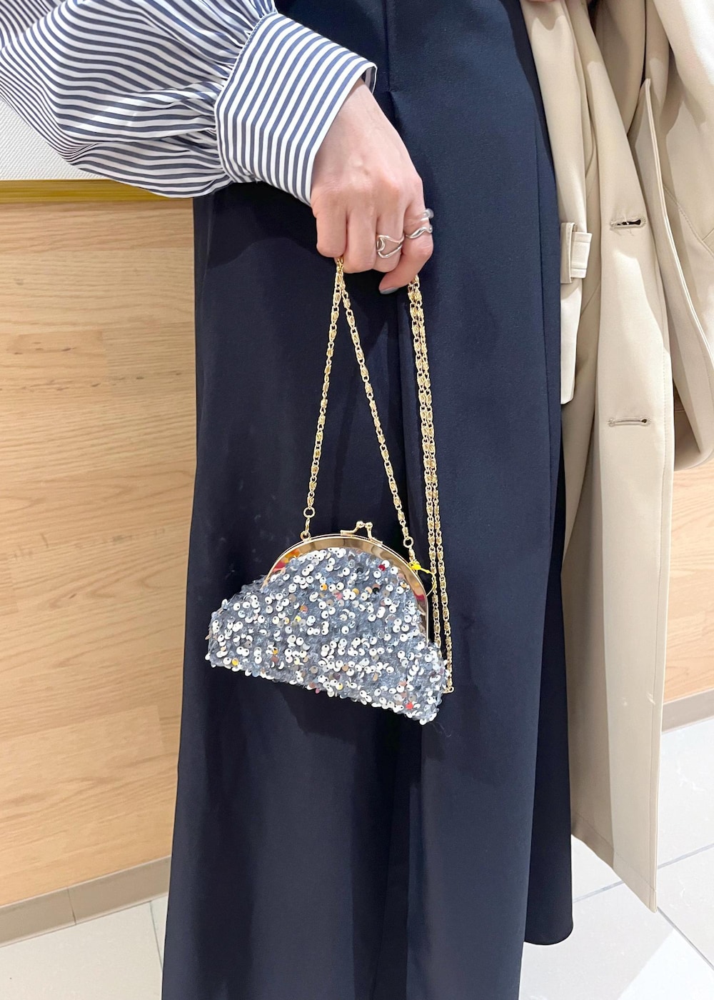 グレー系のショルダーバッグ、ブルー系のシャツ/ブラウス、ベージュ系のトレンチコートを着用したレディースの春コーディネートの8枚目の写真