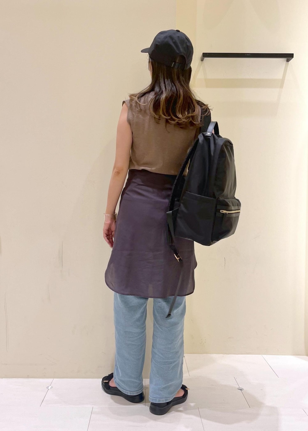 ブルー系のデニムパンツ、ブラック系のサンダル、ブラック系のバックパック/リュックを着用したレディースの夏コーディネートの3枚目の写真