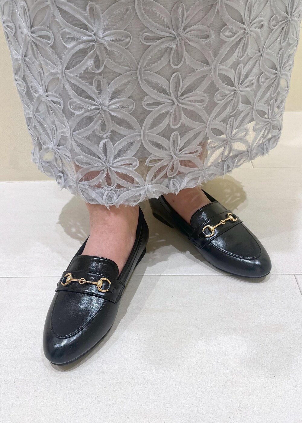 ブラック系のローファー、グレー系のスカート、ホワイト系のシャツ/ブラウスを着用したレディースの春コーディネートの9枚目の写真