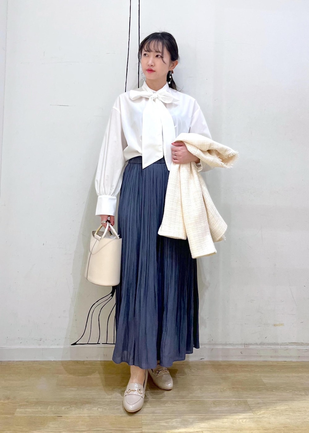 ブルー系のスカート、ベージュ系のローファー、ホワイト系のショルダーバッグを着用したレディースの冬コーディネートの3枚目の写真