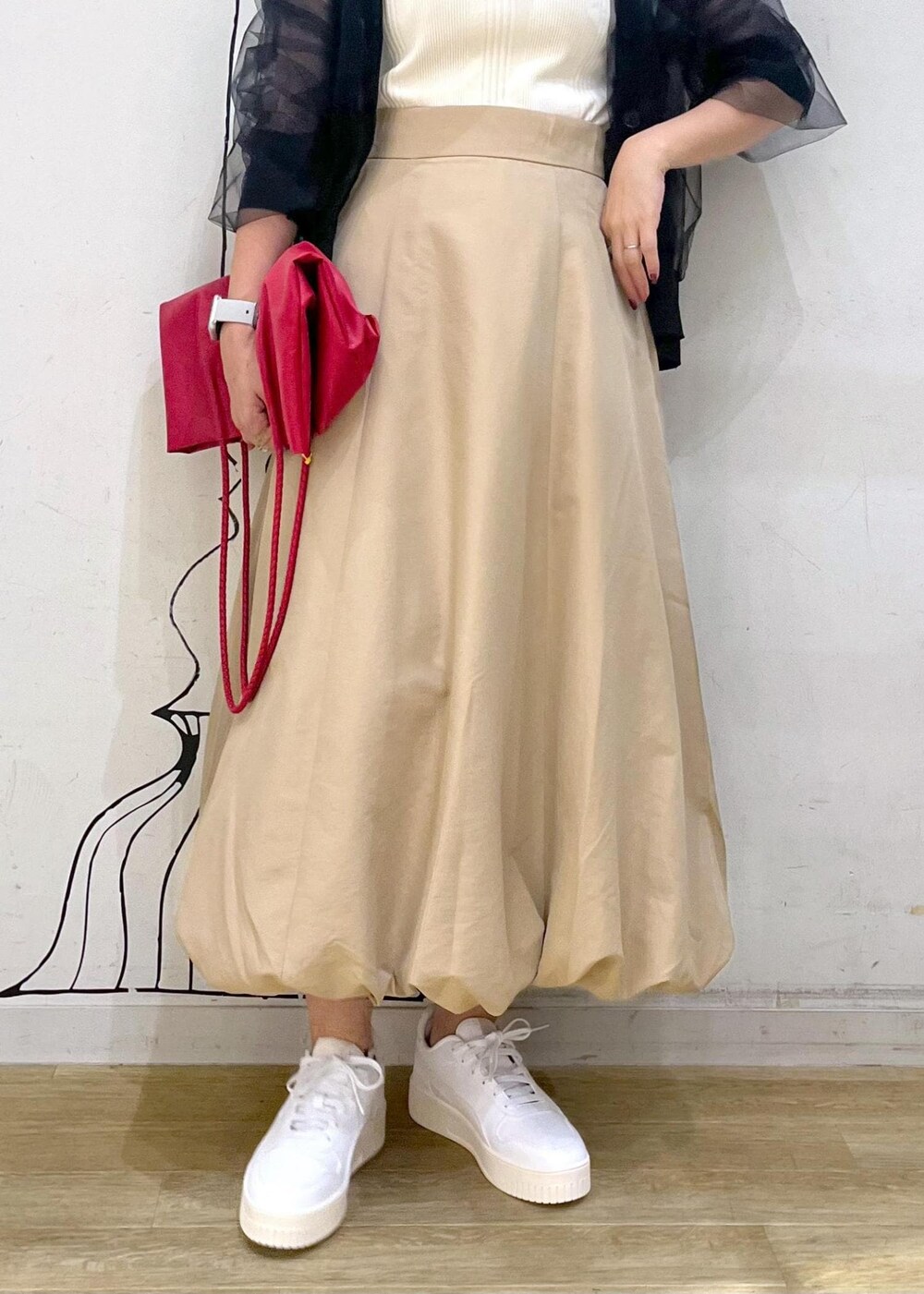 イエロー系のスカート、ブラック系のカーディガン/ボレロ、ホワイト系のスニーカーを着用したレディースの秋コーディネートの7枚目の写真