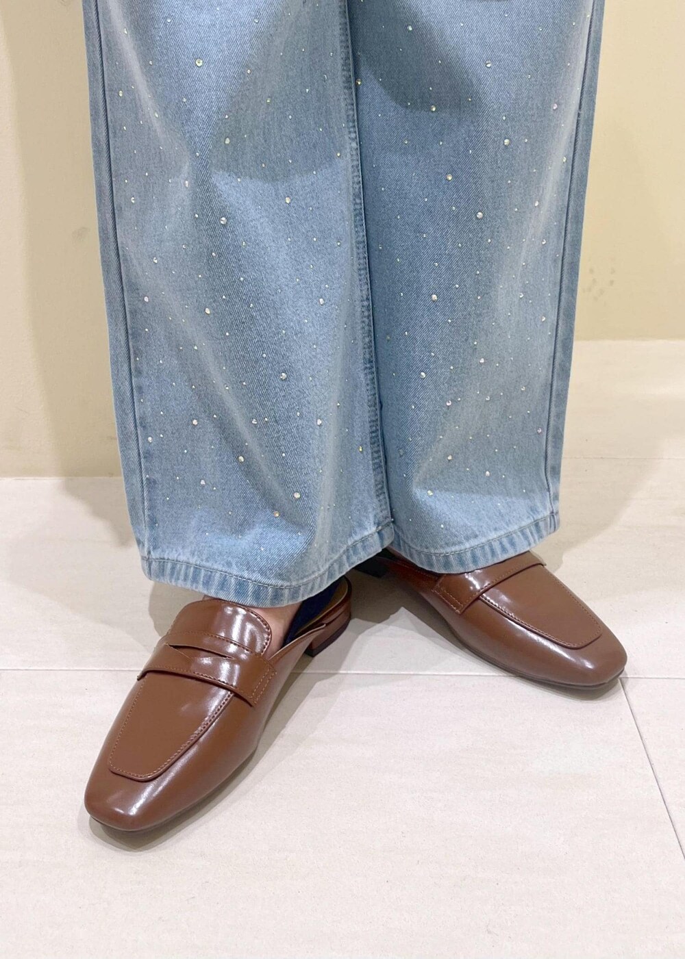 ベージュ系のハンドバッグ、ブルー系のデニムパンツ、ブルー系のベストを着用したレディースの春コーディネートの9枚目の写真