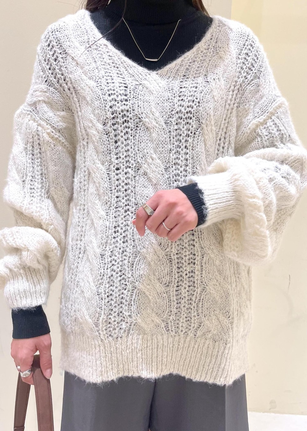 ブラック系のニット/セーター、ブラック系のブーツ、ブラウン系のショルダーバッグを着用したレディースの秋コーディネートの6枚目の写真