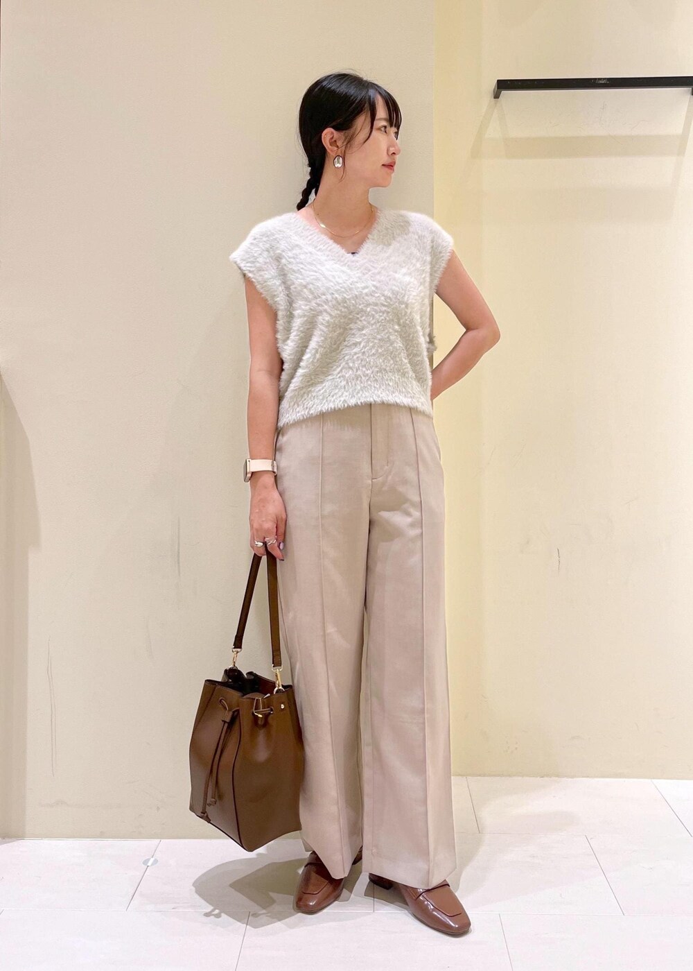 イエロー系のローファー、ベージュ系のその他パンツ、ブラウン系のショルダーバッグを着用したレディースの夏コーディネートの2枚目の写真