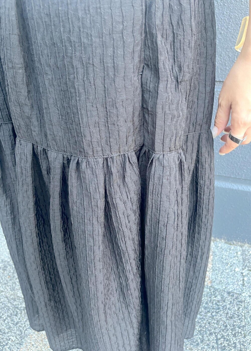 グレー系のテーラードジャケット、ブラウン系のトートバッグ、ブラック系のスカートを着用したレディースの夏コーディネートの7枚目の写真