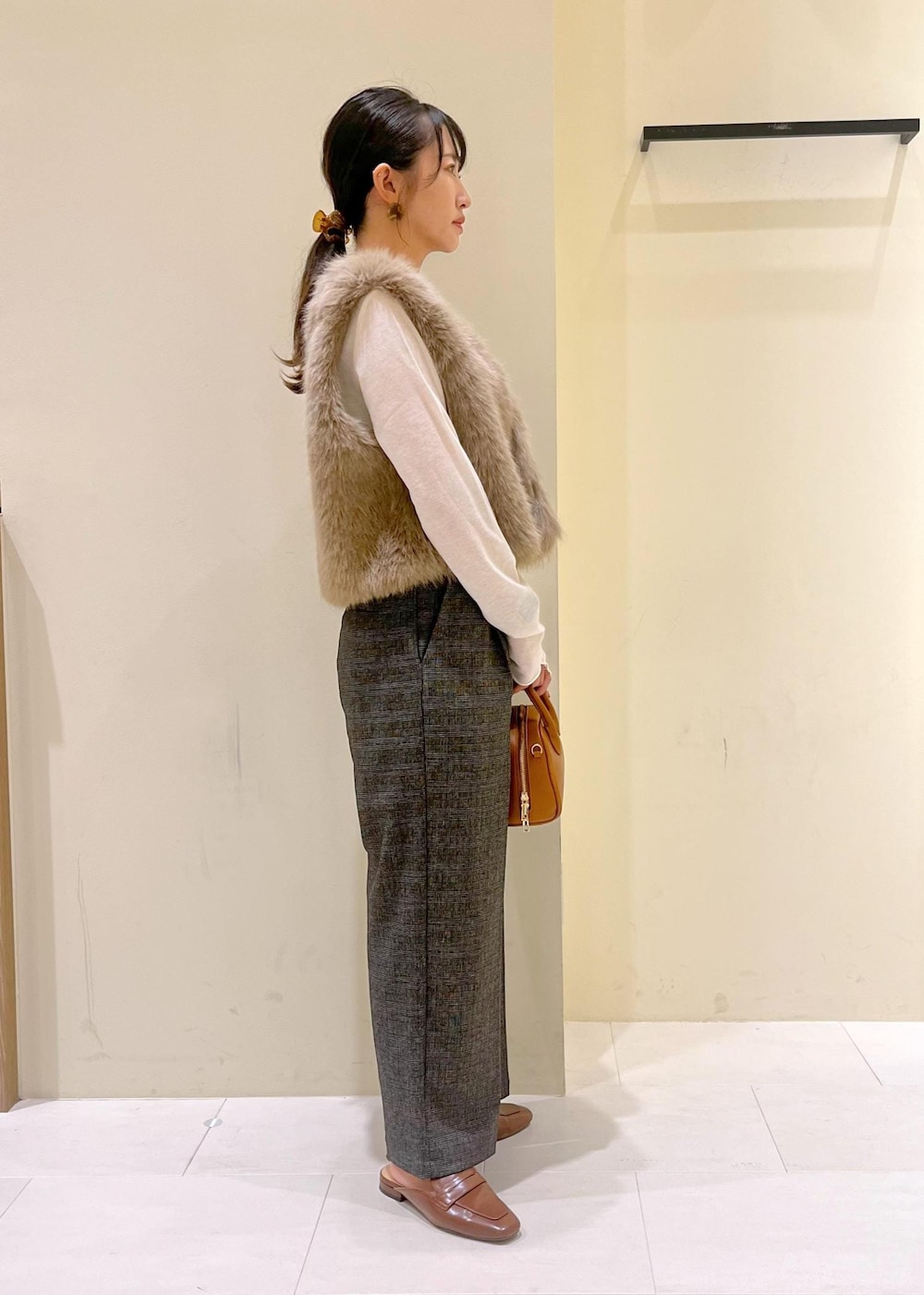 ブラウン系のベスト、ホワイト系のTシャツ/カットソー、グレー系のスラックスを着用したレディースの秋コーディネートの3枚目の写真