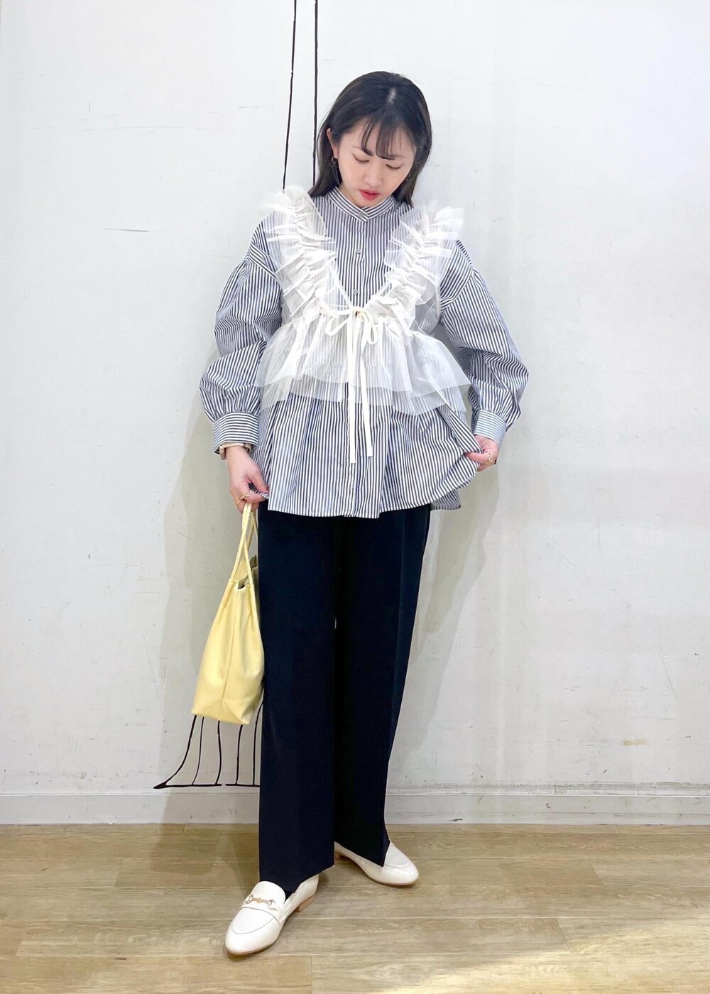 ホワイト系のベスト、ブルー系のその他パンツ、イエロー系のトートバッグを着用したレディースの冬コーディネートの2枚目の写真