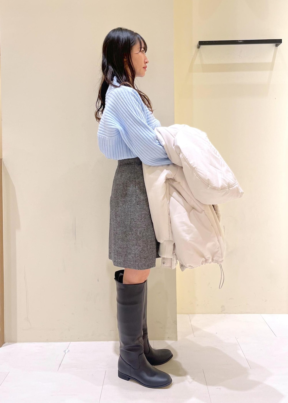 ブラック系のブーツ、ブラウン系のショルダーバッグ、ブルー系のニット/セーターを着用したレディースの冬コーディネートの2枚目の写真