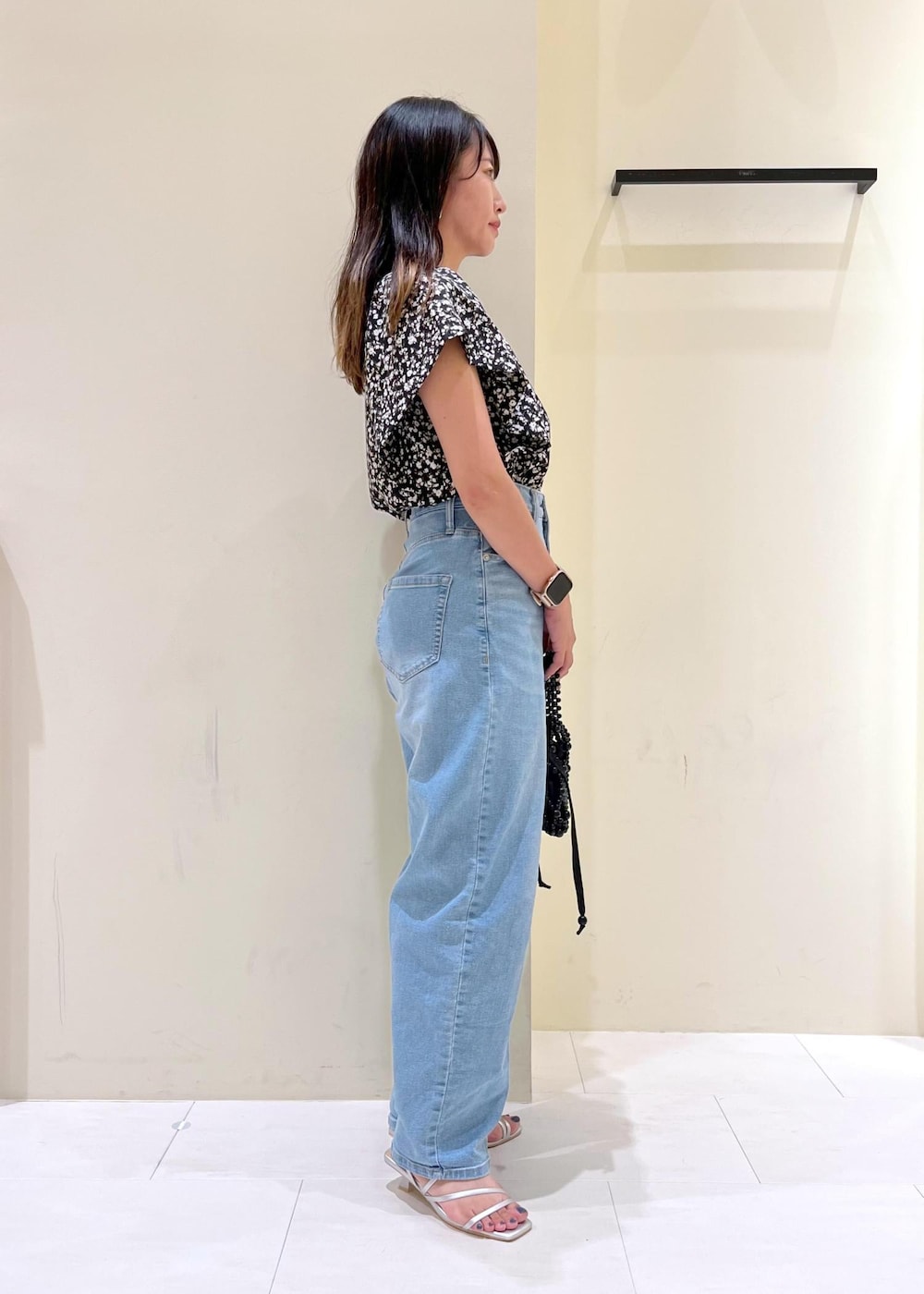 ブルー系のデニムパンツ、ブラック系のハンドバッグ、シルバー系のサンダルを着用したレディースの夏コーディネートの3枚目の写真