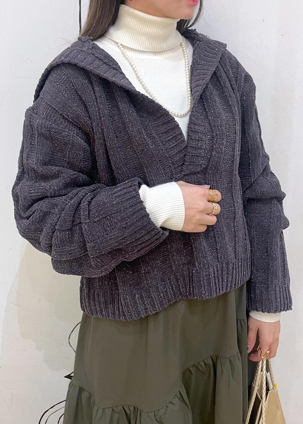 ホワイト系のニット/セーター、ブラック系のバレエシューズ、グリーン系のスカートを着用したレディースの冬コーディネートの5枚目の写真