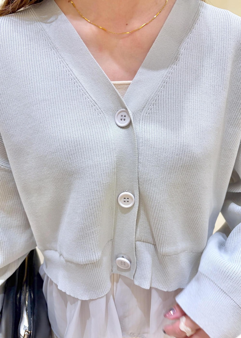 ブラック系のショルダーバッグ、ブラック系のパンプス、ホワイト系のスカートを着用したレディースの春コーディネートの5枚目の写真