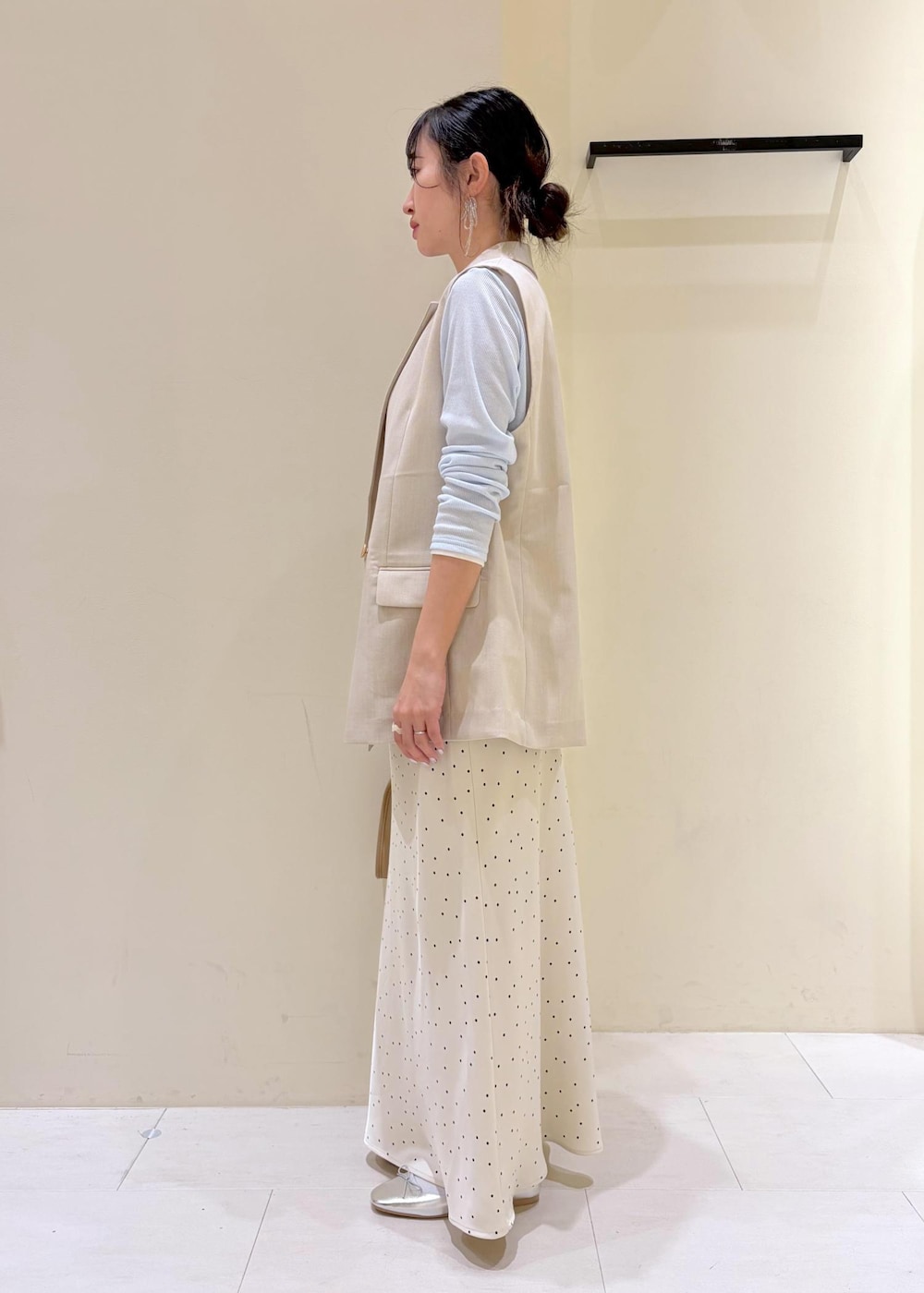 ベージュ系のボストンバッグ、ブルー系のTシャツ/カットソー、ベージュ系のベストを着用したレディースの春コーディネートの4枚目の写真