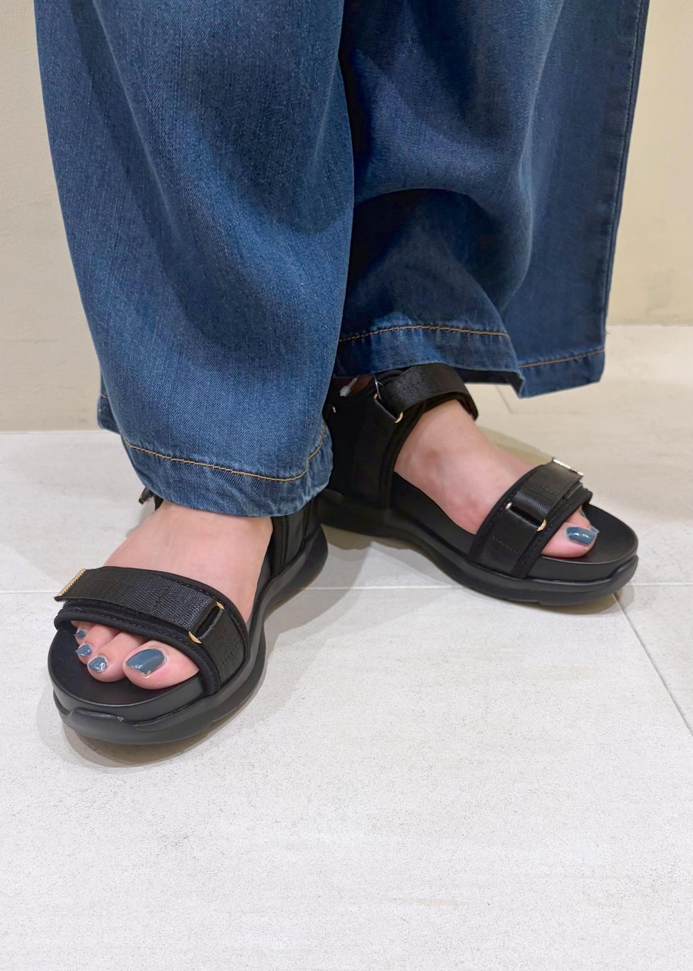 ブラック系のサンダル、ブラック系のニット/セーター、ブルー系のデニムパンツを着用したレディースの夏コーディネートの10枚目の写真