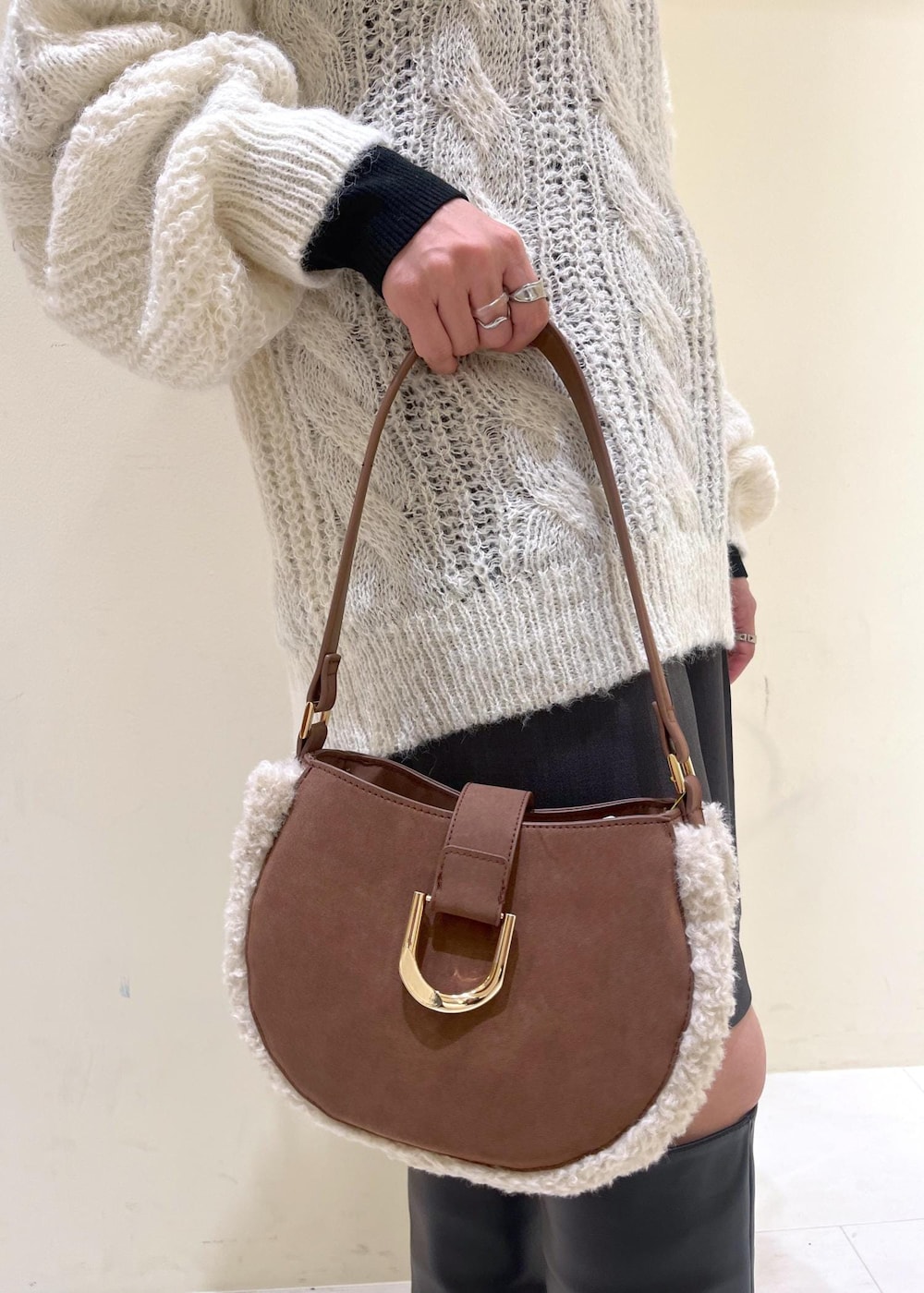 ブラック系のニット/セーター、ブラック系のブーツ、ブラウン系のショルダーバッグを着用したレディースの秋コーディネートの10枚目の写真