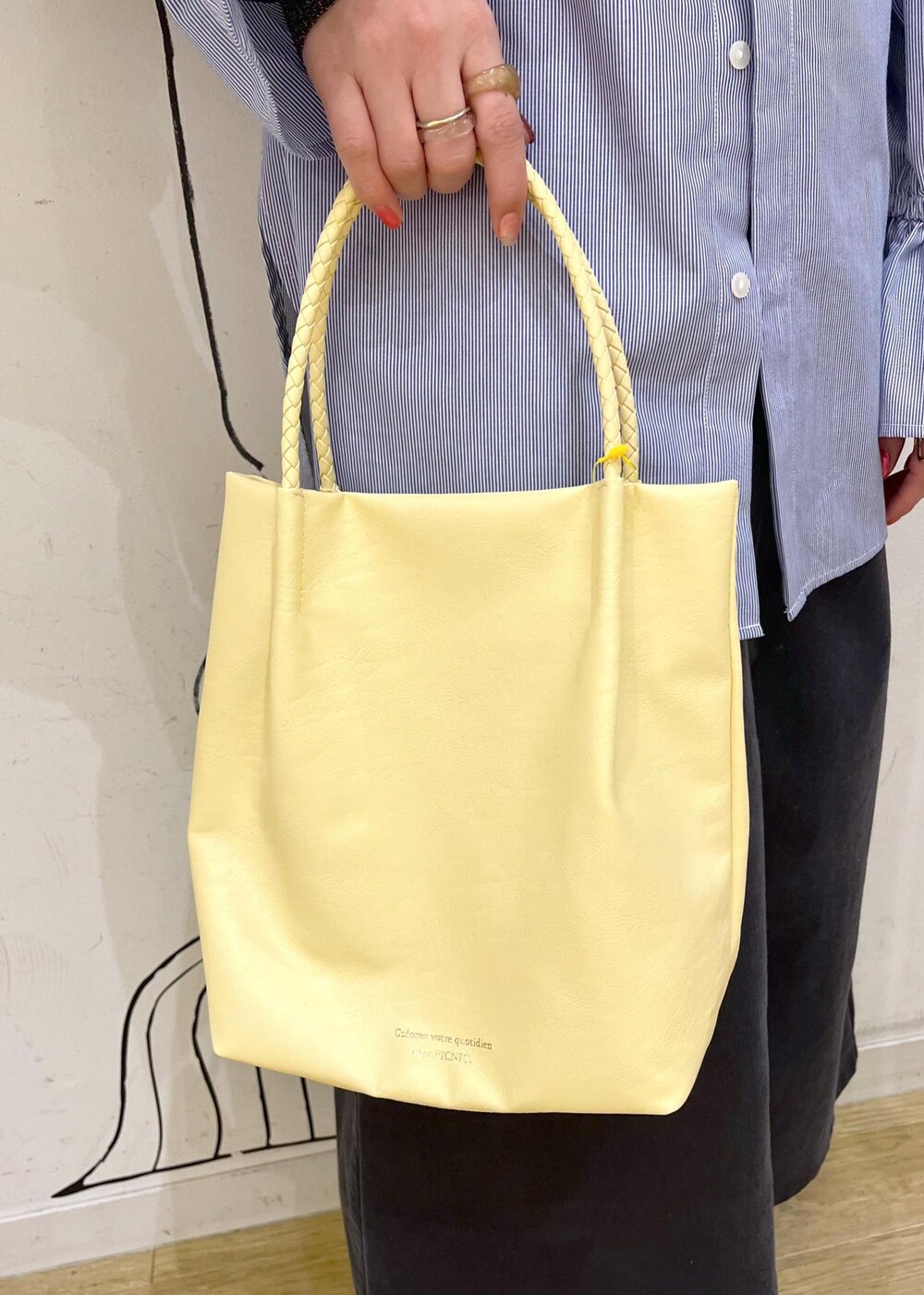 イエロー系のトートバッグ、グレー系のスカート、ブルー系のシャツ/ブラウスを着用したレディースの冬コーディネートの7枚目の写真