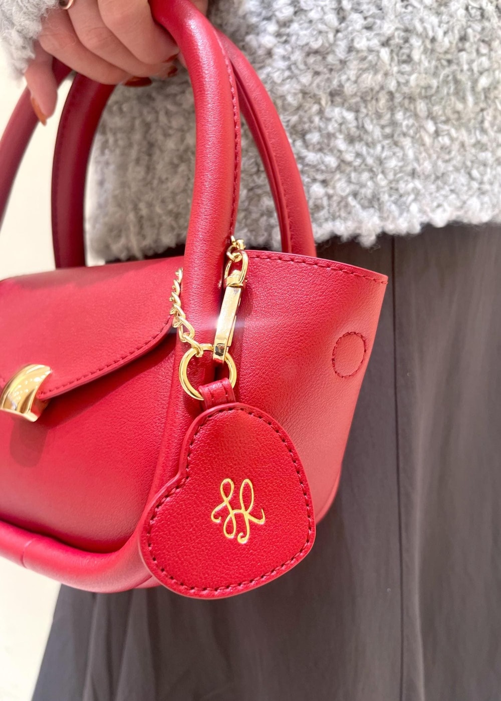 ホワイト系のニット/セーター、グレー系のスカート、レッド系のショルダーバッグを着用したレディースの冬コーディネートの10枚目の写真