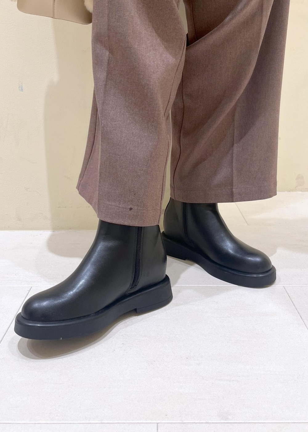 ベージュ系のスラックス、ホワイト系のシャツ/ブラウス、ブラック系のブーツを着用したレディースの冬コーディネートの10枚目の写真