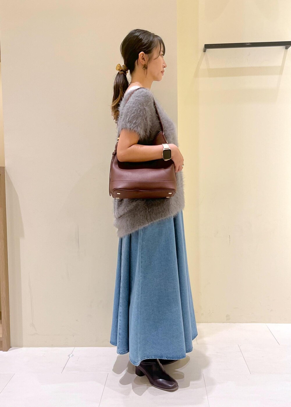 グレー系のタンクトップ、ブルー系のスカート、グレー系のベストを着用したレディースの秋コーディネートの3枚目の写真