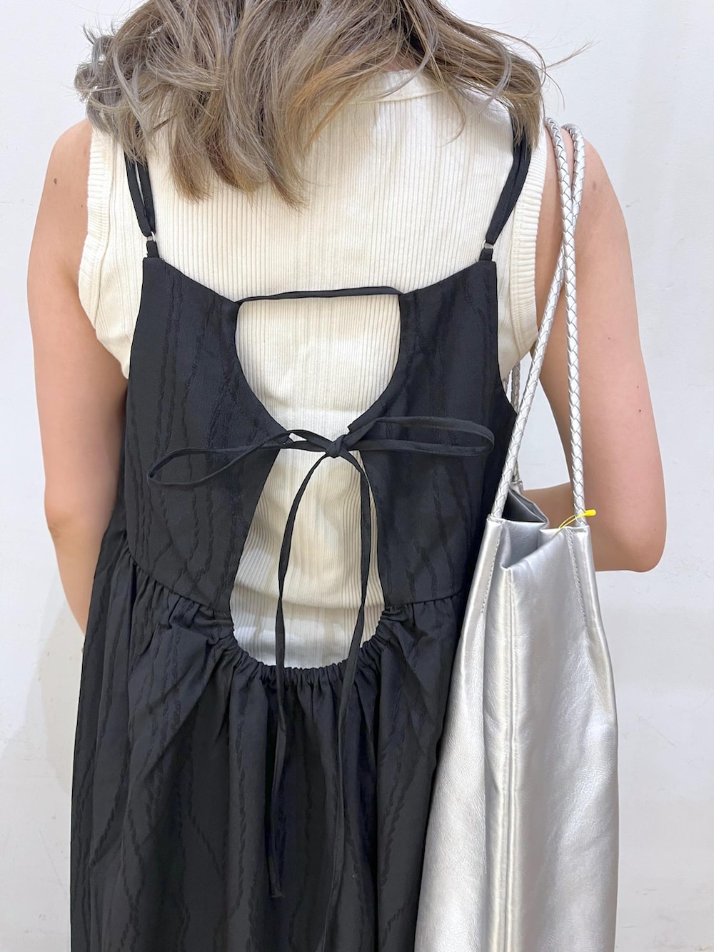 シルバー系のトートバッグ、ベージュ系のタンクトップ、ブラック系のワンピースを着用したレディースの夏コーディネートの5枚目の写真